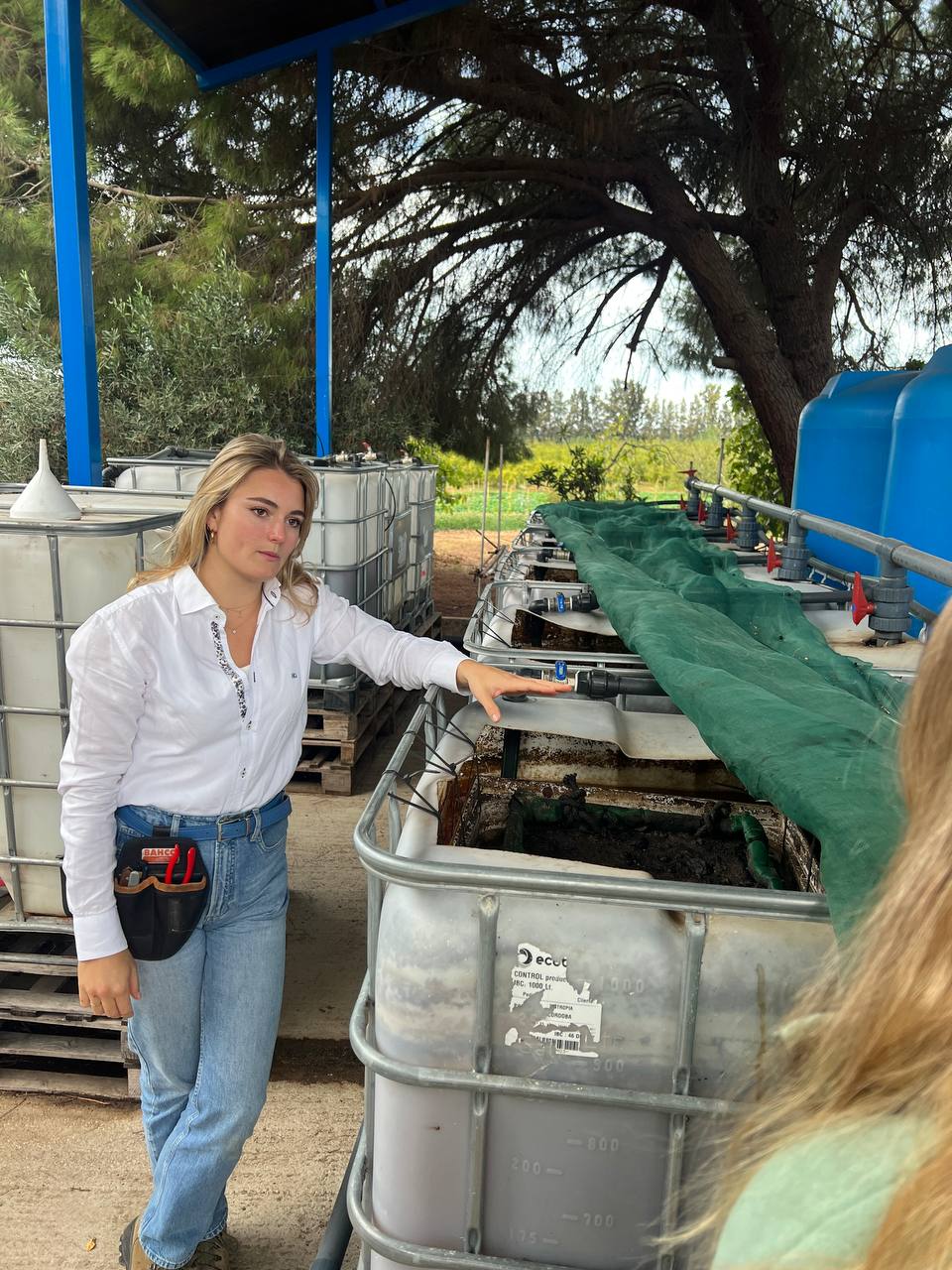 Lilli à côté des cuves où la ferme prépare son compost et ses micro-organismes