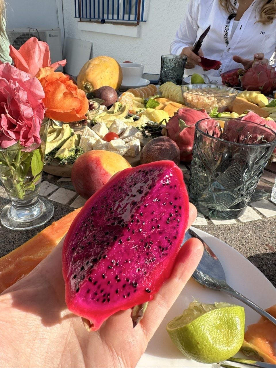 Une pitaya rouge coupée en deux, avec la table du déjeuner derrière